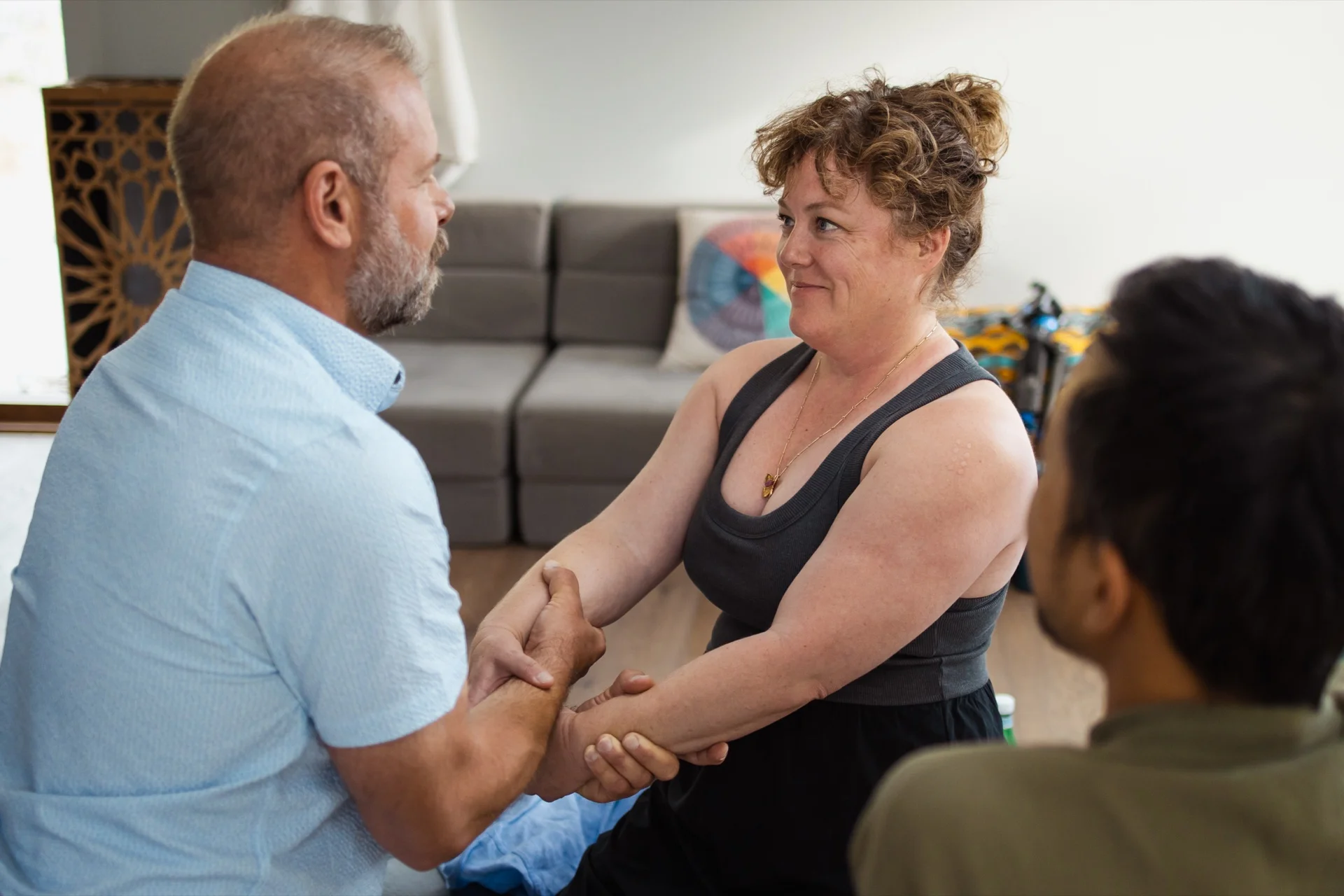 Justin and Shannon in the dyad practice, arms held, eyes meeting, with Edmond beside them