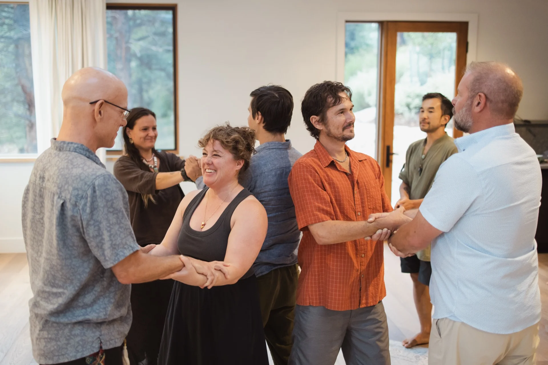 The room standing in pairs, arms held, a participant laughing as she is met
