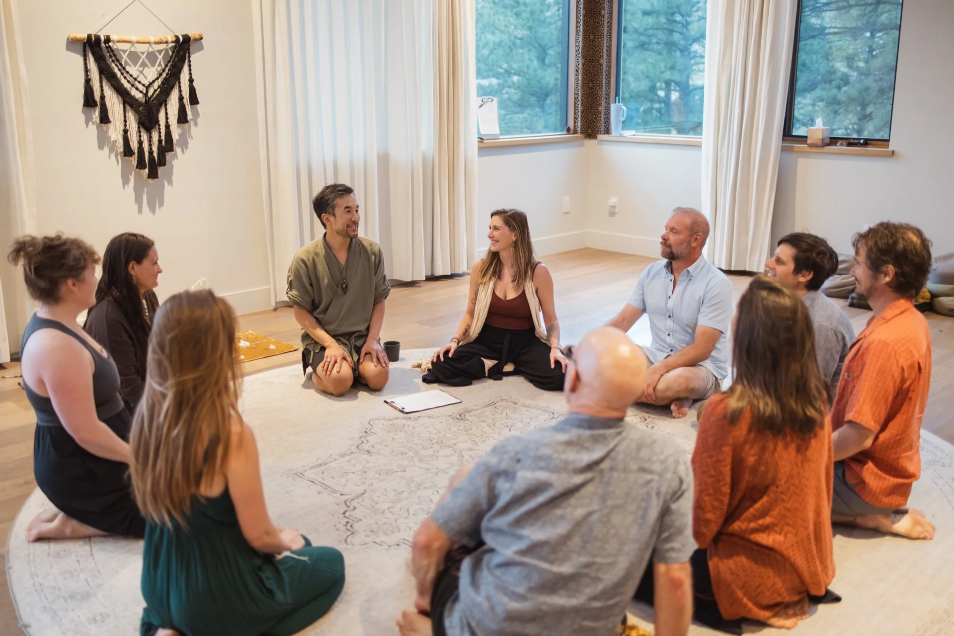 The founding cohort seated in a circle on the rug, Edmond and Kiki at the head